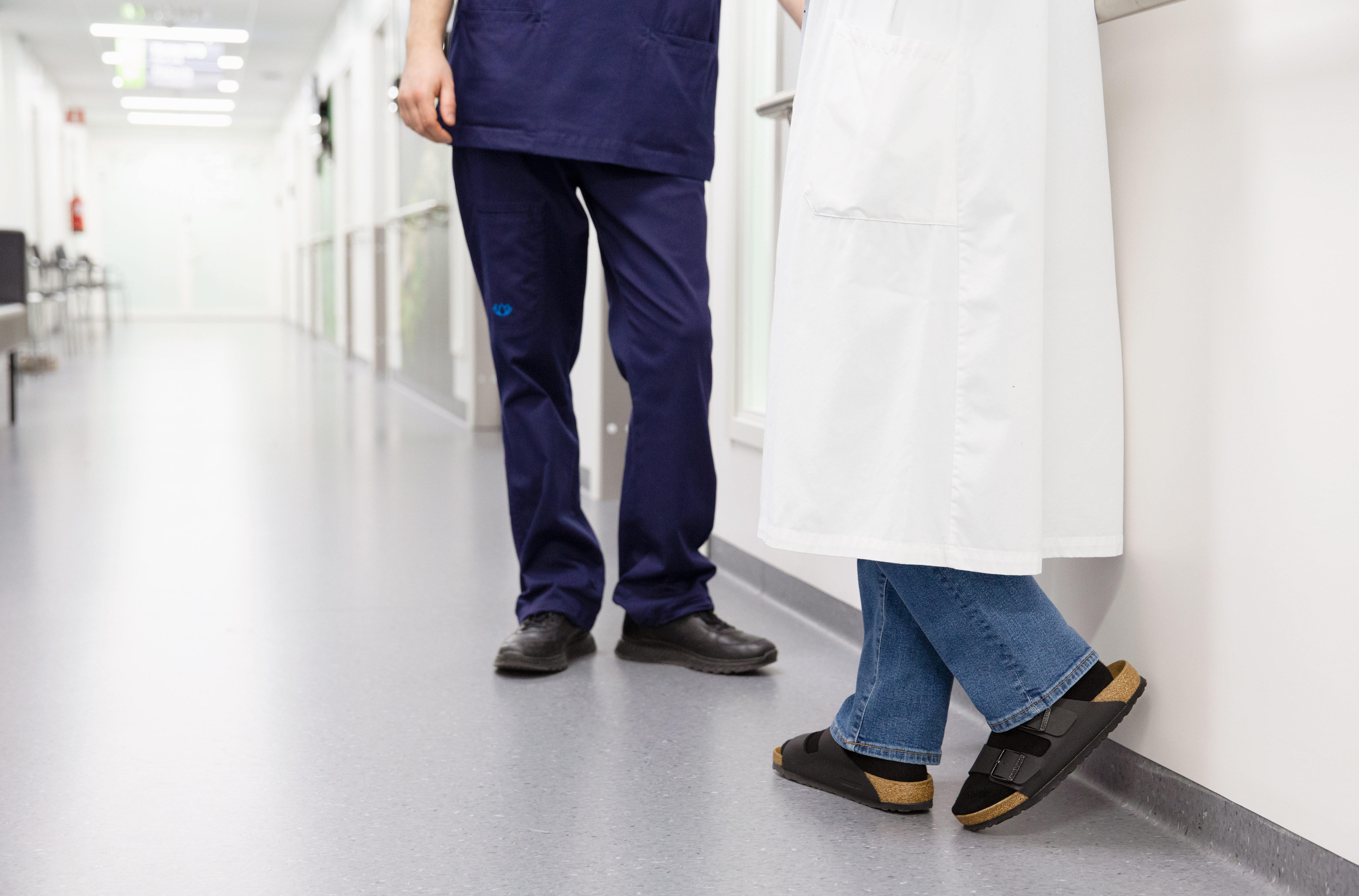 Lääkäri ja sairaanhoitaja seisovat sairaalan käytävällä.