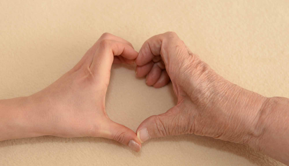 Nuoren ja vanhuksen kädet yhdessä sydämen muodossa